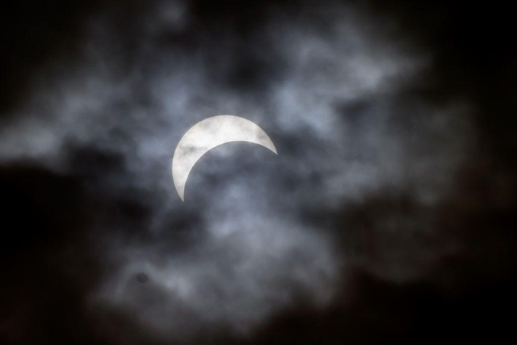 SYRACUSE, NEW YORK - APRIL 08: A view of the partial solar eclipse behind the clouds as seen from the quad at Syracuse University on April 08, 2024 in Syracuse, New York. Millions of people have flocked to areas across North America that are in the "path of totality" in order to experience a total solar eclipse. During the event, the moon will pass in between the sun and the Earth, appearing to block the sun. (Photo by Roy Rochlin/Getty Images)